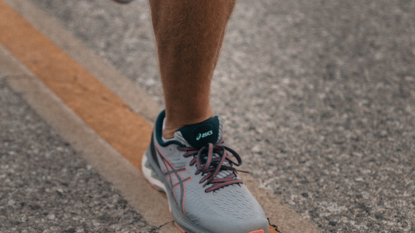 Close-up of a runner’s ankle and Achilles tendon on the road — where Achilles tendonitis pain is felt in Tampa runners and hybrid athletes.