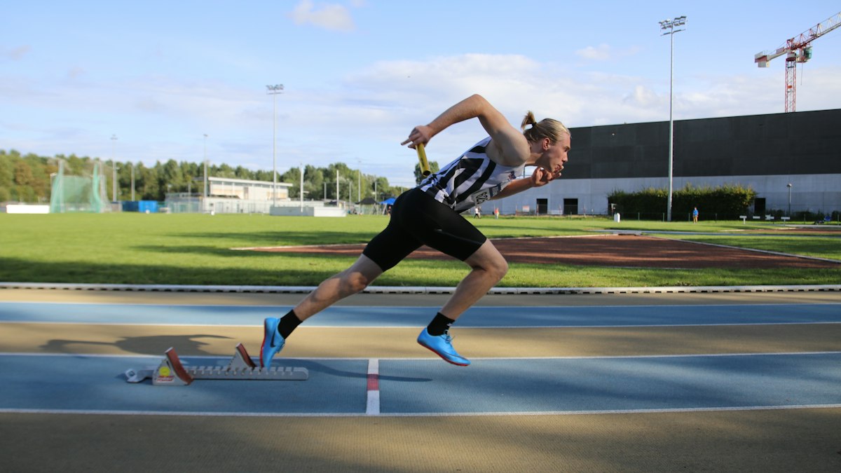 Sprinter driving out of the blocks on an outdoor track &mdash; hamstring strain physical therapy for athletes at Forward Physio Tampa