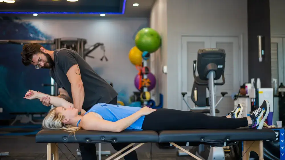 Forward Physio doctor of physical therapy assessing an athlete’s overhead shoulder range of motion on a treatment table — part of a shoulder pain physical therapy evaluation in Tampa.