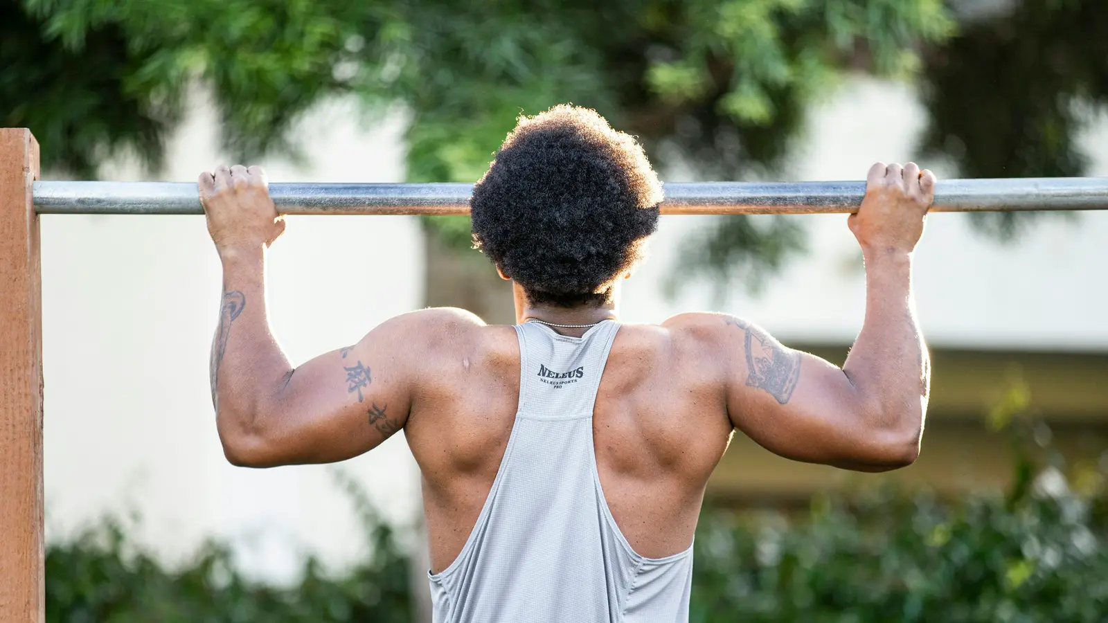 Athlete mid pull-up on an outdoor bar, forearms and elbows working hard — the grip-heavy training that tennis elbow physical therapy in Tampa gets lifters and hybrid athletes back to.